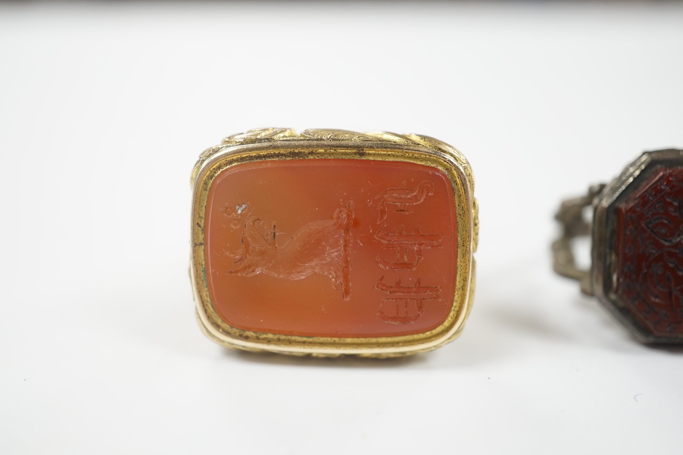 A 19th century gilt metal overlaid and carnelian set fob seal, 36mm, together with a white metal and chalcedony set fob seal, the matrix carved with Persian script.